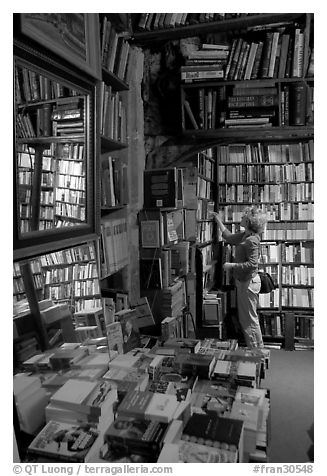 Picking-up a book in Shakespeare and Co bookstore. Quartier Latin, Paris, France (black and white)