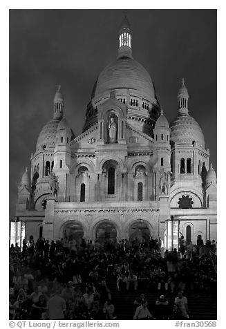 Tourists sitting on the stairs of the Sacre coeur basilic in Montmartre at night. Paris, France