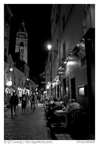 Dinners and narrow pedestrian street at night, Montmartre. Paris, France (black and white)
