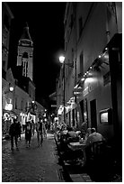 Dinners and narrow pedestrian street at night, Montmartre. Paris, France (black and white)