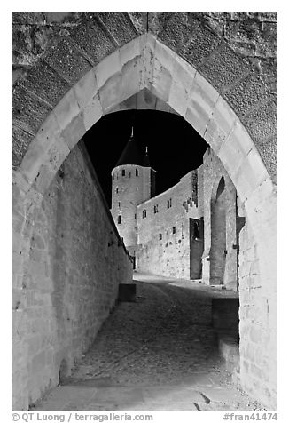 Ramparts and tower framed by gate at night. Carcassonne, France (black and white)