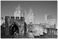 Main entrance of medieval city  with child and adult walking in. Carcassonne, France (black and white)