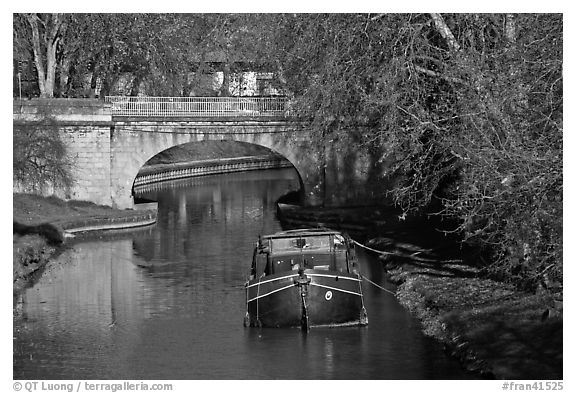 Tranquil scene with barge, bridge, and trees, Canal du Midi. Carcassonne, France