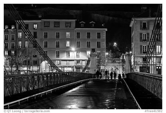 Pedestrians on suspension bridge at night. Grenoble, France