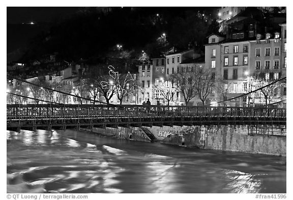 Suspension bridge at night with Christmas lights reflected in river. Grenoble, France (black and white)