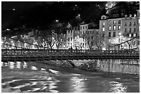 Suspension bridge at night with Christmas lights reflected in river. Grenoble, France (black and white)