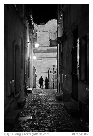 Narrow cobblestone passageway at night next to arena. Arles, Provence, France (black and white)