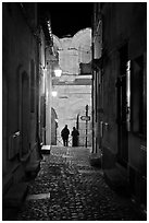 Narrow cobblestone passageway at night next to arena. Arles, Provence, France (black and white)