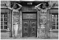 Wooden door framed by sculptures. Aix-en-Provence, France (black and white)