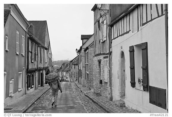 Pedestrian with umbrella in narrow street, Provins. France (black and white)