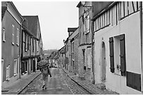 Pedestrian with umbrella in narrow street, Provins. France (black and white)