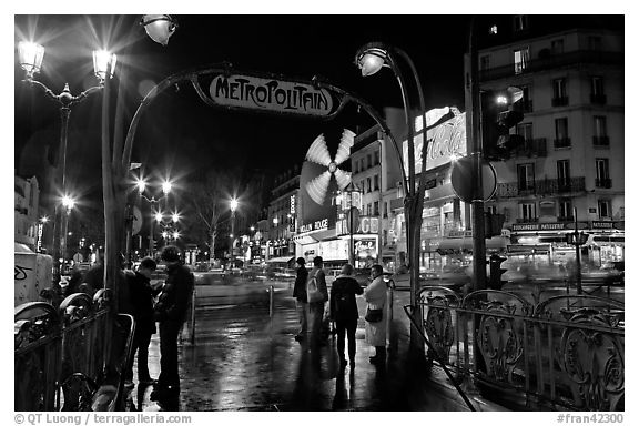 Metro entrance, boulevard, and Moulin Rouge on rainy night. Paris, France (black and white)