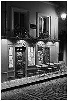 Restaurant with red facade and cobblestone street by night, Montmartre. Paris, France (black and white)