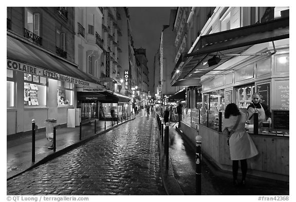 Woman buying food on street at night. Quartier Latin, Paris, France (black and white)