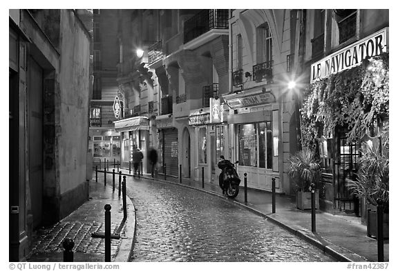 Street with cobblestone pavement and restaurants by night. Quartier Latin, Paris, France (black and white)