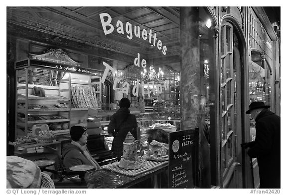 Elderly man entering bakery with people inside. Paris, France (black and white)