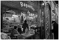 Elderly man entering bakery with people inside. Paris, France ( black and white)