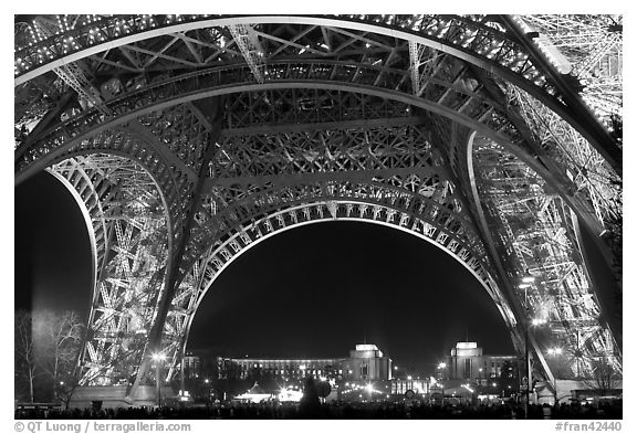 Palais de Chaillot seen through the base of Eiffel Tower by night. Paris, France (black and white)