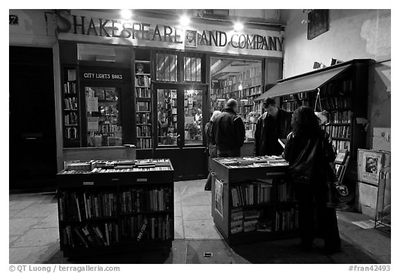 People reading in front of bookstore at night. Quartier Latin, Paris, France (black and white)