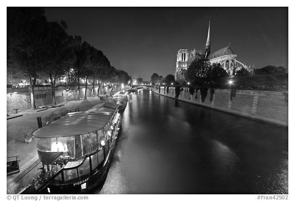 Quay, lighted boats, Seine River and Notre Dame at night. Paris, France