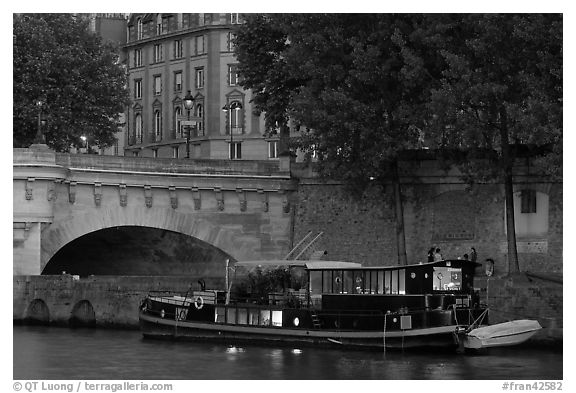 Lighted live-in barge, quay, and Pont-Neuf. Paris, France (black and white)