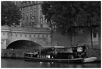 Lighted live-in barge, quay, and Pont-Neuf. Paris, France (black and white)