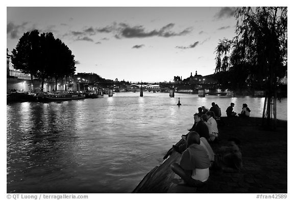 People sitting on tip of Ile de la Cite at sunset. Paris, France (black and white)