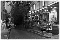 Cobblestone street and restaurant at dusk, Montmartre. Paris, France (black and white)