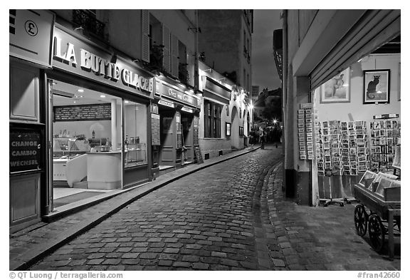 Narrow cobblestone street and businesses at night, Montmartre. Paris, France