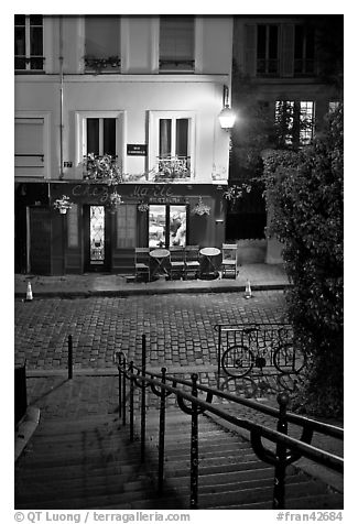 Hillside stairs on butte, street and restaurant at night, Montmartre. Paris, France (black and white)