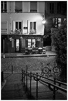 Hillside stairs on butte, street and restaurant at night, Montmartre. Paris, France (black and white)