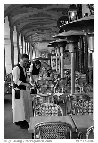 Waiters and customer, place des Vosges arcades. Paris, France