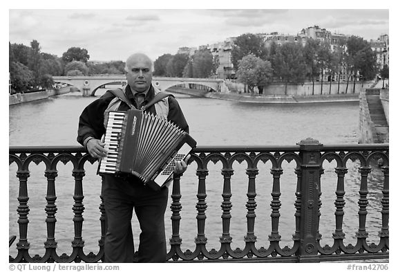 Street musician playing accordeon on River Seine bridge. Paris, France (black and white)