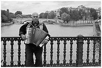 Street musician playing accordeon on River Seine bridge. Paris, France (black and white)