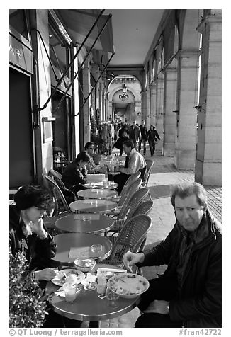 Couple eating at an outdoor table in the Palais Royal arcades. Paris, France (black and white)