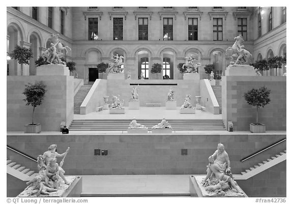 Ancient sculptures in display in Louvre Museum room. Paris, France (black and white)