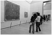 Tourists looking at a large impressionist painting of a lilly pond. Paris, France (black and white)