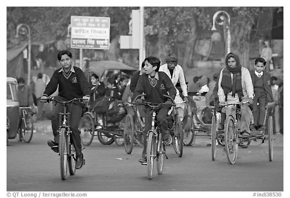 Children riding bikes in rickshaws on way to school. New Delhi, India (black and white)