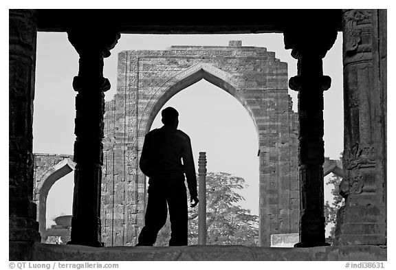 Man at entrance of ruined Quwwat-ul-Islam mosque. New Delhi, India (black and white)