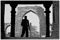 Man at entrance of ruined Quwwat-ul-Islam mosque. New Delhi, India (black and white)