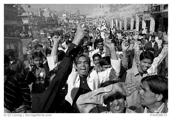 Young men celebrating and spraying wedding party in the street. Jodhpur, Rajasthan, India