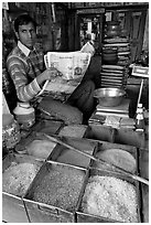 Man with newspaper selling grains, Sardar Market. Jodhpur, Rajasthan, India (black and white)