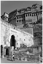 Couple walking below gate and high walls, Mehrangarh Fort. Jodhpur, Rajasthan, India ( black and white)