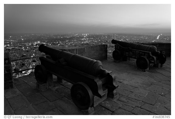 Cannons on top of Mehrangarh Fort, and city lights and dusk. Jodhpur, Rajasthan, India (black and white)