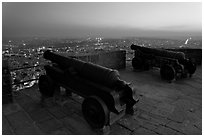 Cannons on top of Mehrangarh Fort, and city lights and dusk. Jodhpur, Rajasthan, India (black and white)