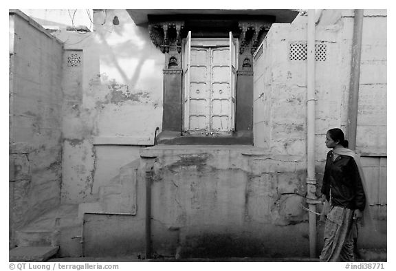 Woman walks infront of blue tinted whitewashed wall. Jodhpur, Rajasthan, India (black and white)
