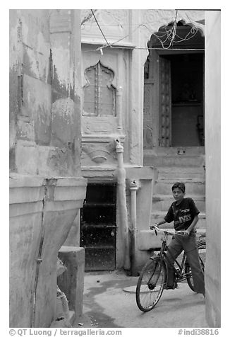 Boy riding a bicycle in a narrow old town street. Jodhpur, Rajasthan, India (black and white)