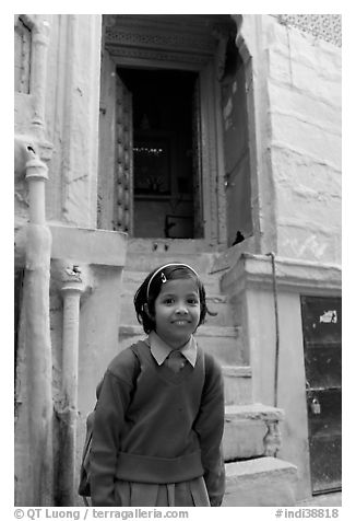 Schoolgirl standing in front of a house with blue tint. Jodhpur, Rajasthan, India (black and white)