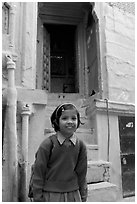 Schoolgirl standing in front of a house with blue tint. Jodhpur, Rajasthan, India (black and white)