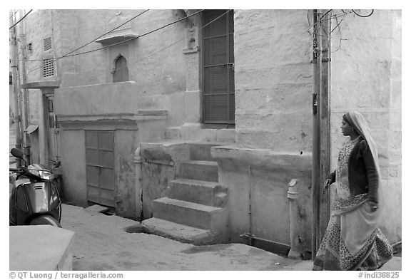Woman walking in narrow street with blue walls. Jodhpur, Rajasthan, India (black and white)